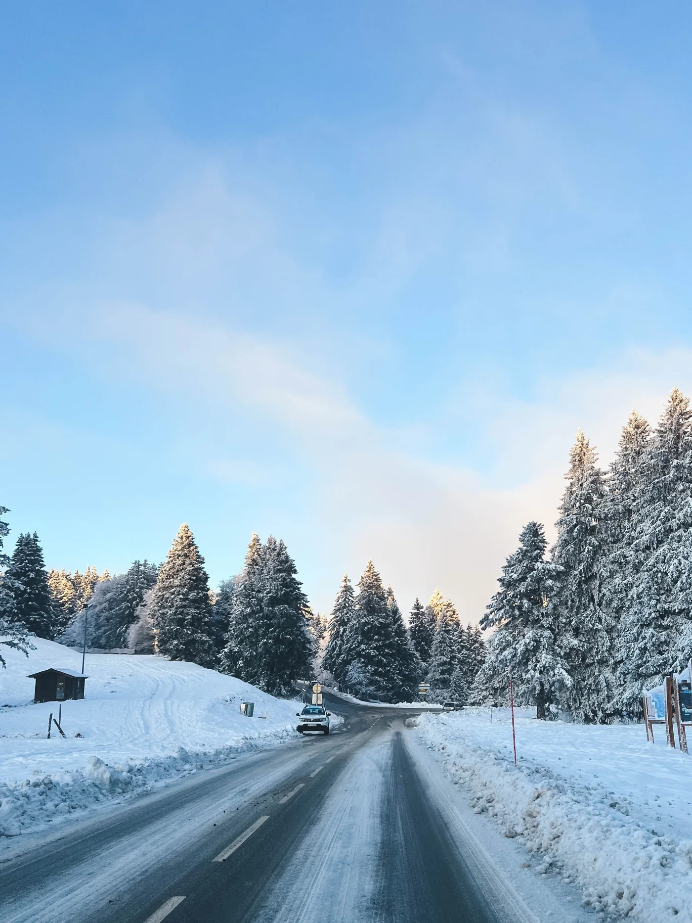 Verschneite Strasse durch einen winterlichen Alpenwald